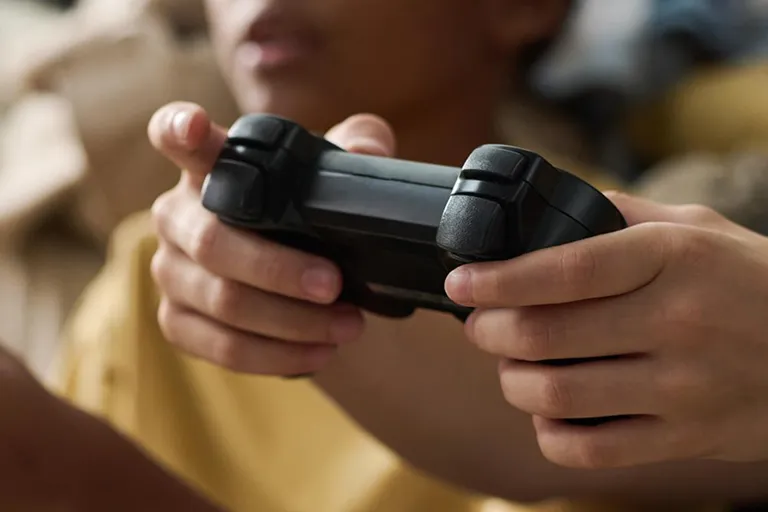 Jeune joueur tenant une manette de console avec concentration dans un bar à jeux